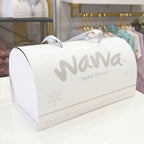 Caja de regalo blanca con asas, Nawa baby design en el lateral y detalles decorativos.