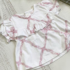 Blusa de algodón blanca con estampado rosa tipo lazos y falda con volante