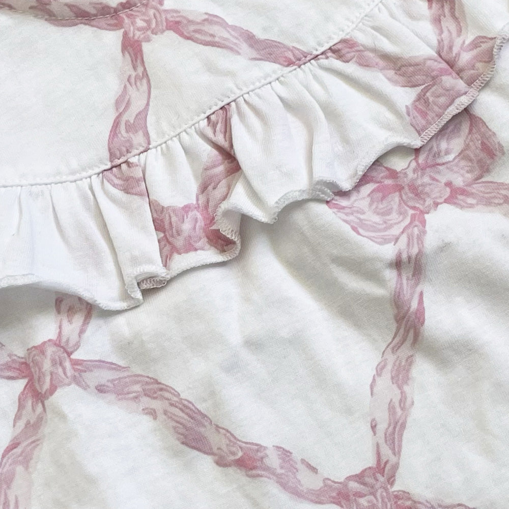 Blusa blanca con estampado rosa; volante fruncido en la parte delantera