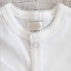 Body blanco para bebé con cuello elástico y broche central con volante