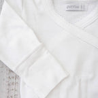Detalle del body blanco: costuras cruzadas y ribete con acabado picot