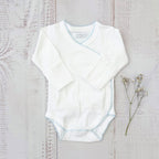 Body infantil blanco con ribete celeste picot y manga larga cruzada