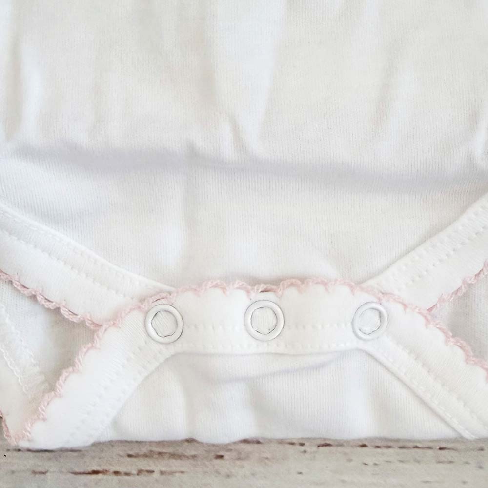 Parte inferior del body blanco con volantes picot rosado y botones a presión