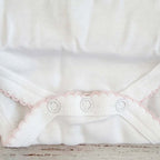 Parte inferior del body blanco con volantes picot rosado y botones a presión