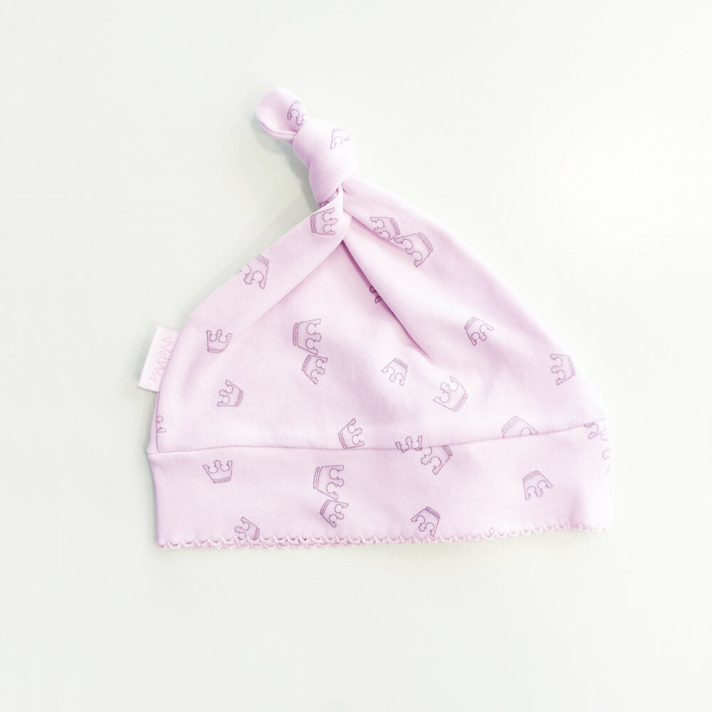 Gorro infantil rosado con nudo en la parte superior y estampado repetido de coronas.