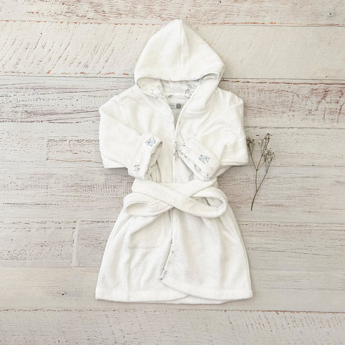 Bata de baño infantil blanca con capucha, cierre frontal y cinturón tipo kimono.