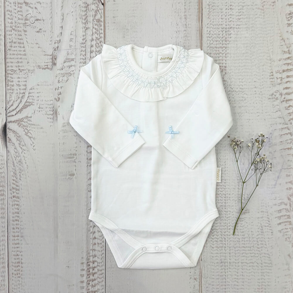 Body blanco manga larga con cuello fruncido, lazos celestes y botones a presión en la entrepierna.