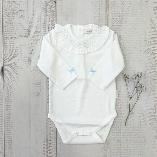 Body blanco manga larga con cuello fruncido, lazos celestes y botones a presión en la entrepierna.
