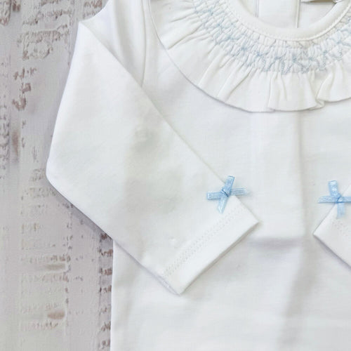 Body blanco con mangas largas, lazo celeste y volante en el cuello fruncido.