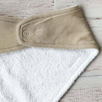 Bandana triangular de tela beige con botones a presión y reverso blanco tipo felpa