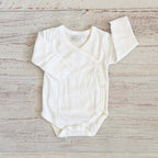 Body básico blanco con cuello redondo y borde picot amarillo; manga larga con puños