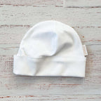 Gorro blanco de bebé con ribete ondulado y etiqueta en un lateral