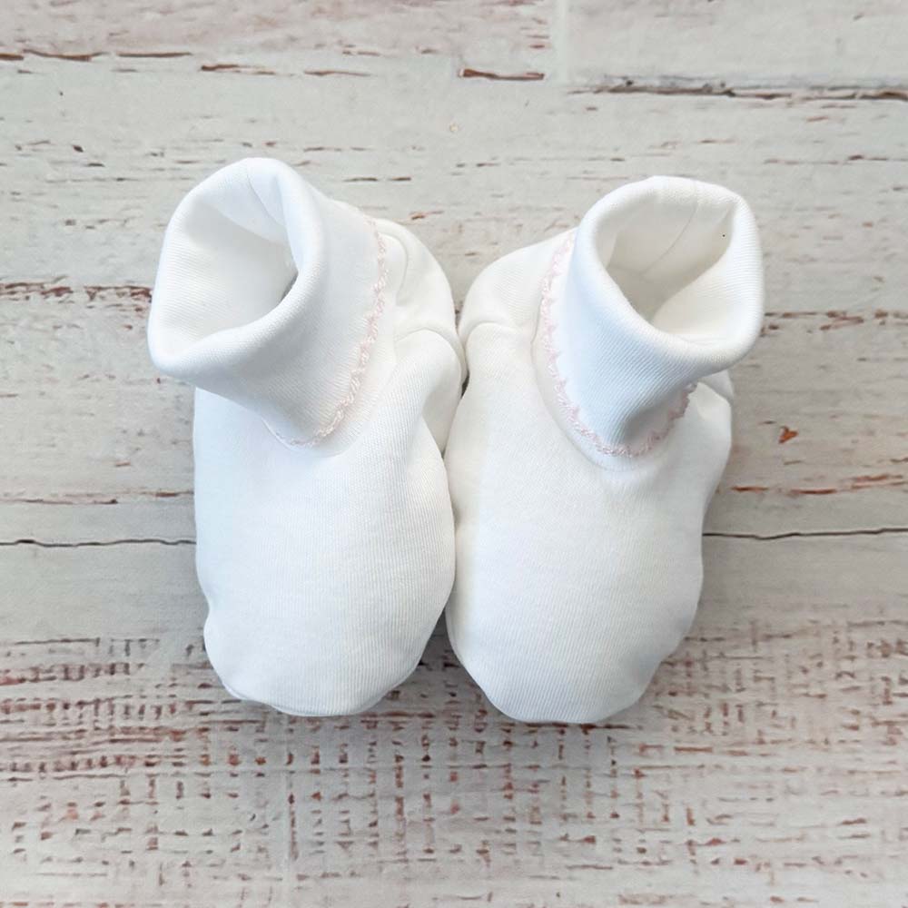 Par de patucos blancos con cuello elástico y costura decorativa rosa