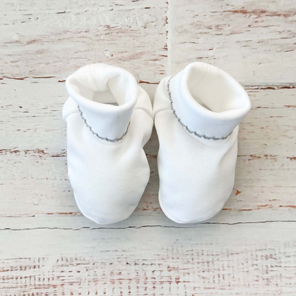 Patucos de bebé blancos con borde concha y detalle decorativo
