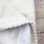 Manta blanca con esquina y ribete picot rosado con pespunte