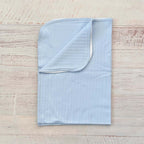 Manta jacquard celeste con borde y diseño trenzado en relieve, doblada