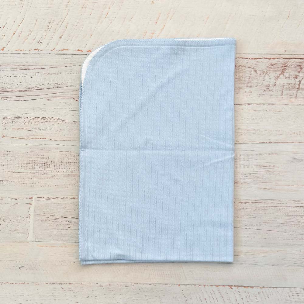 Manta jacquard celeste lisa con borde blanco y caída recta, vista posterior