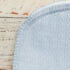Manta jacquard celeste con textura en relieve y pespunte decorativo en el borde