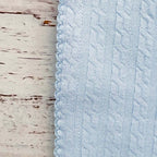 Detalle de tela jacquard celeste con textura y ribete cosido, esquina