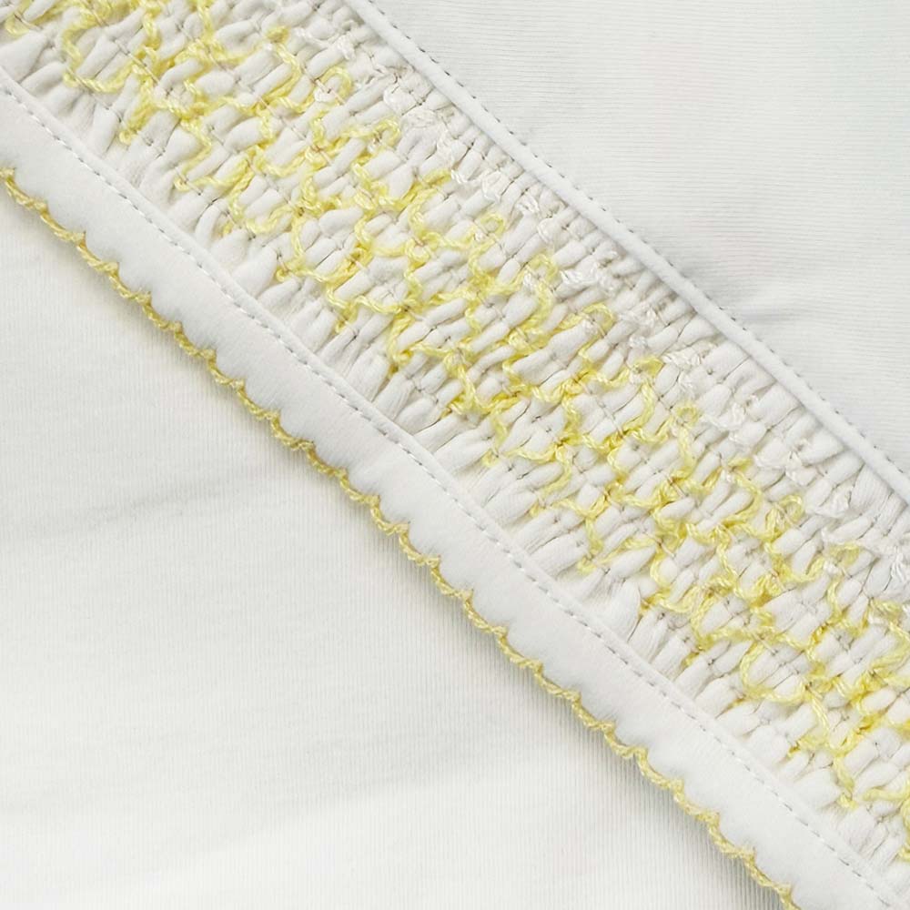 Manta blanca con borde tejido amarillo tipo smock y puntilla elástica