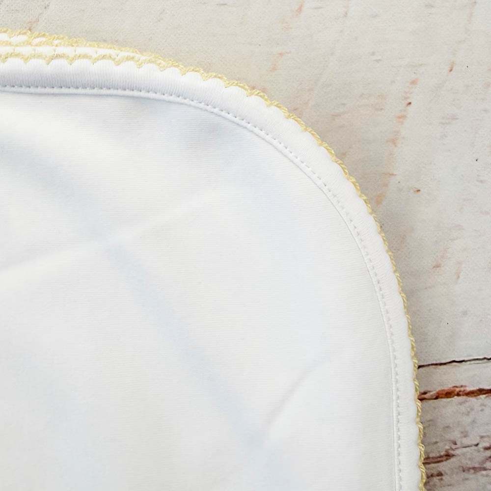 Esquina redondeada de manta blanca con costura y ribete amarillo