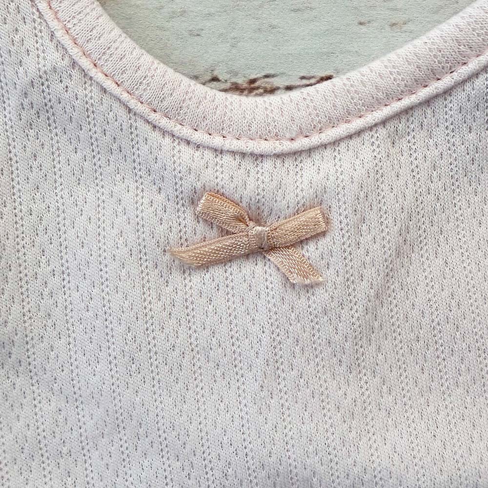 Babero rosa pálido de tela calada con lazo de listón beige y cuello redondo