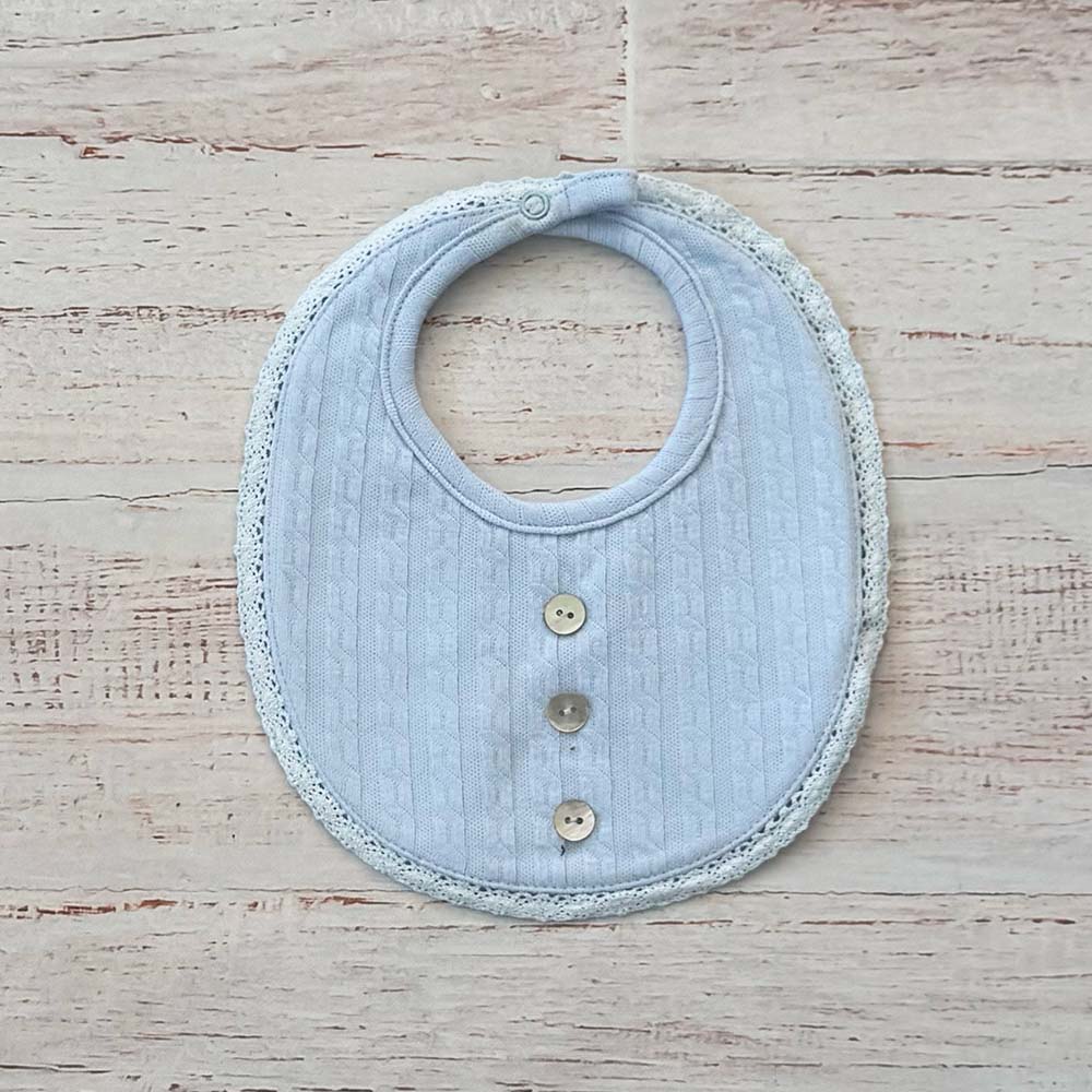Babero de bebé celeste de tejido calado con tres botones al frente y borde festoneado.