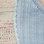 Babero celeste con borde de encaje y tejido acanalado con relieve.