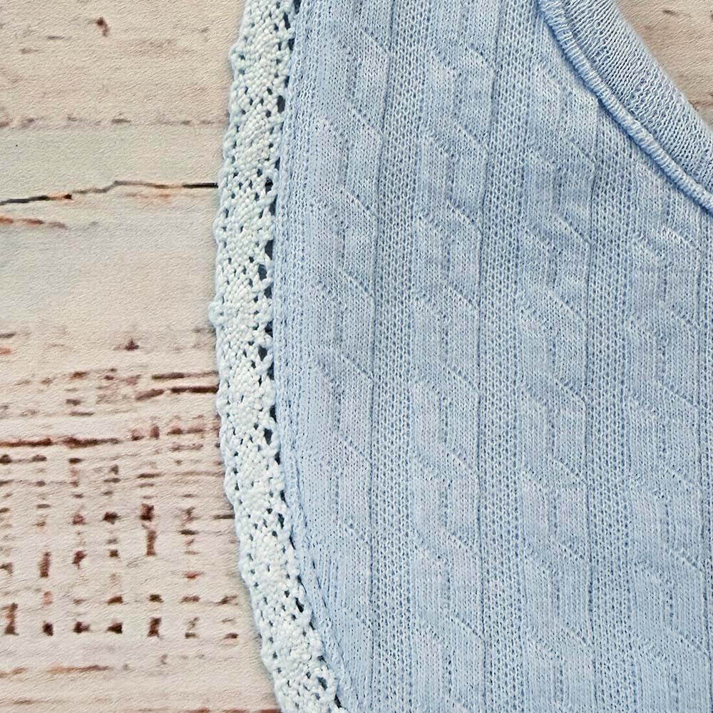 Babero celeste con borde de encaje y tejido acanalado con relieve.