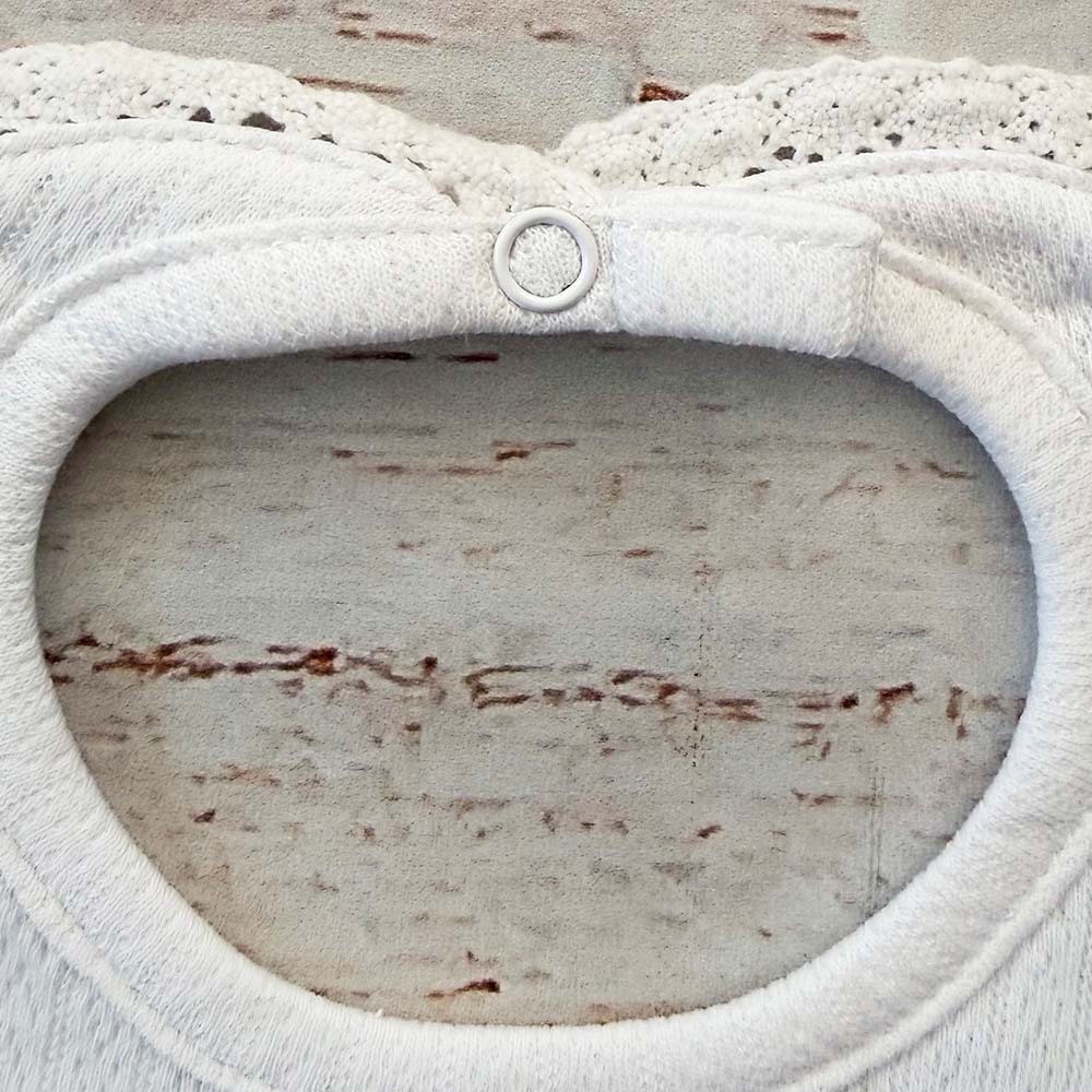 Babero blanco con abertura oval y aro de botón frontal