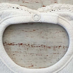 Babero blanco con abertura oval y aro de botón frontal