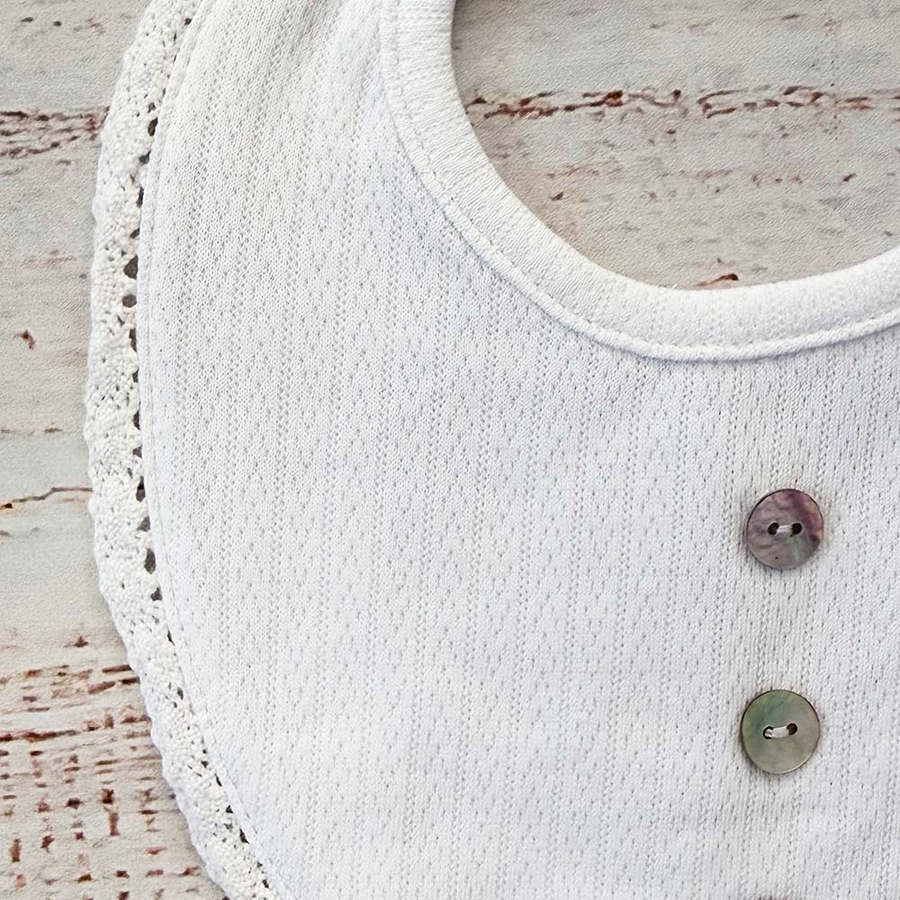 Babero blanco con cuello redondeado y botones metálicos
