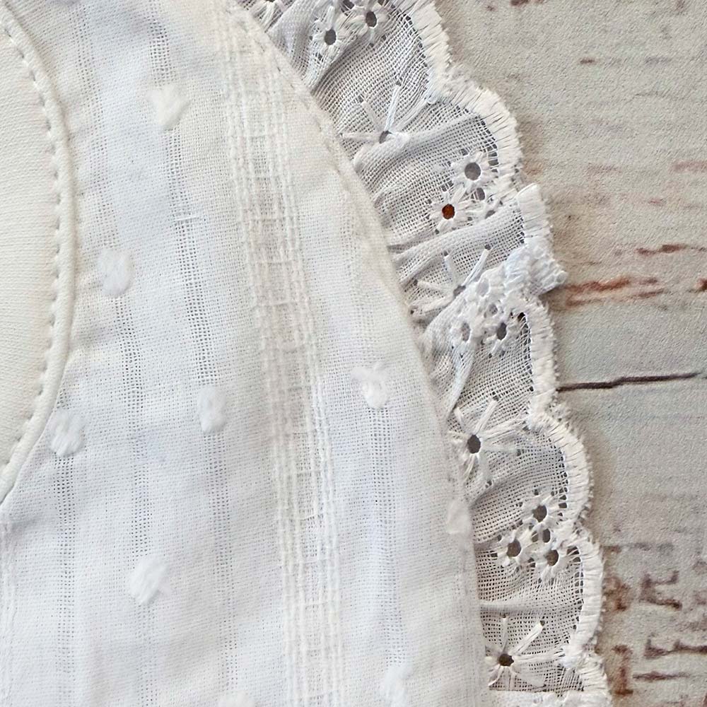 Babero bordado de niña blanco: tela con relieve y volante de encaje floral