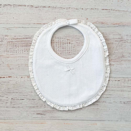 Babero de niña blanco con bordado calado y volante alrededor del cuello, cierre ajustable.