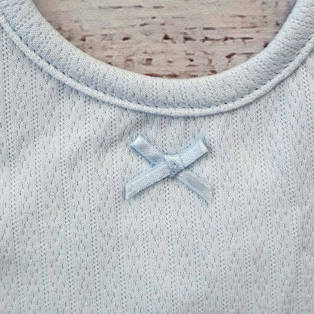 Babero celeste con lazo de satén y cuello acanalado, detalle frontal