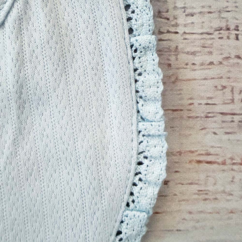 Babero celeste con borde de calado y costura lateral, vista de perfil