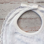 Babero bordado unisex blanco con botón superior y borde de encaje alrededor del cuello