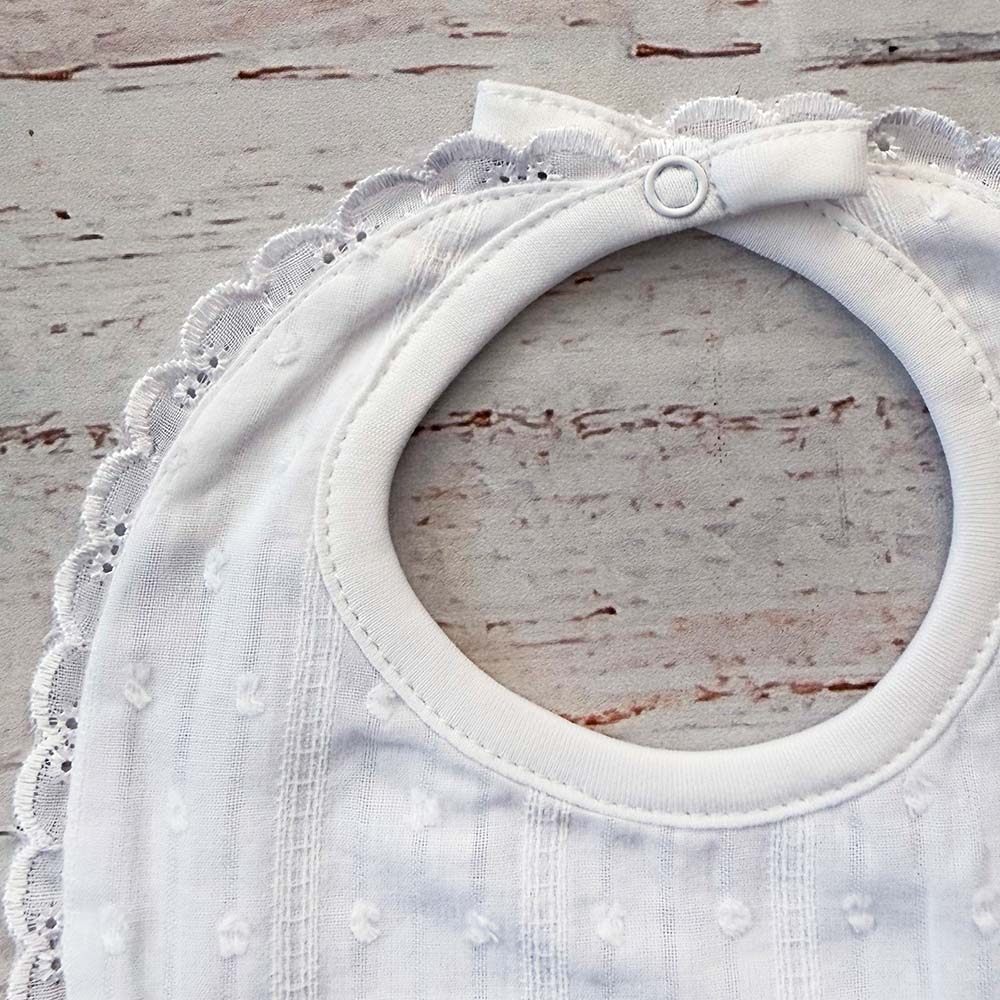 Babero bordado unisex blanco con botón superior y borde de encaje alrededor del cuello
