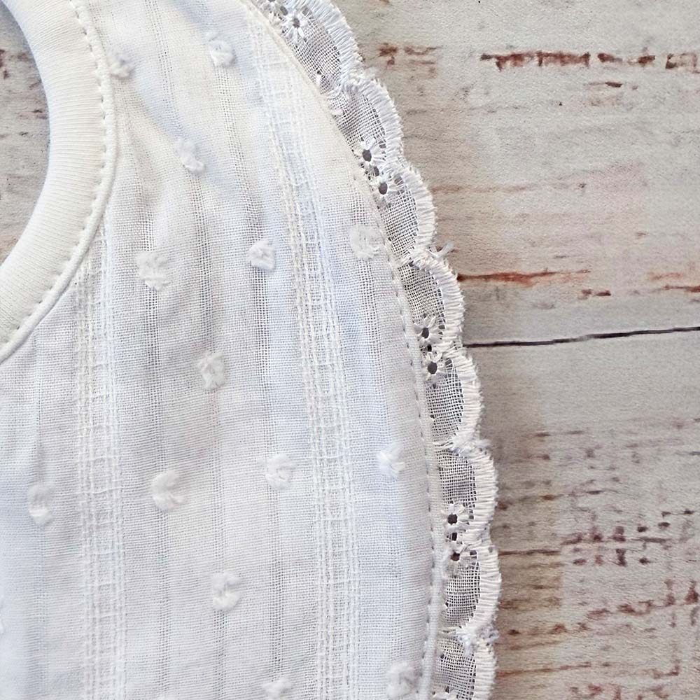 Babero blanco con textura de puntitos bordados y remate de encaje en el lateral