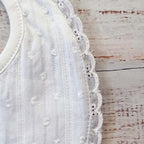 Babero blanco con textura de puntitos bordados y remate de encaje en el lateral