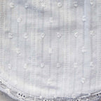 Babero blanco bordado con líneas verticales y relieve de puntitos en la tela