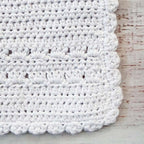 Babero de crochet blanco con franja de puntos y borde ondulado