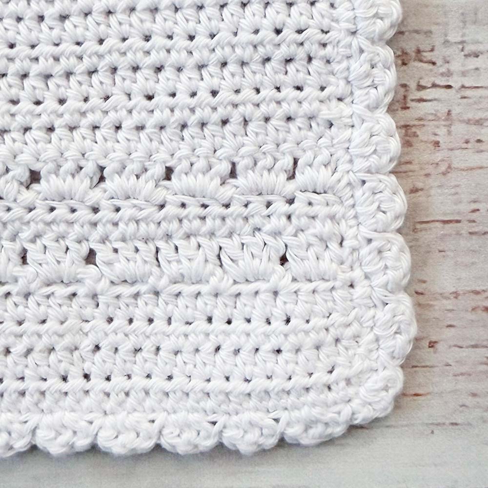 Babero de crochet blanco con franja de puntos y borde ondulado