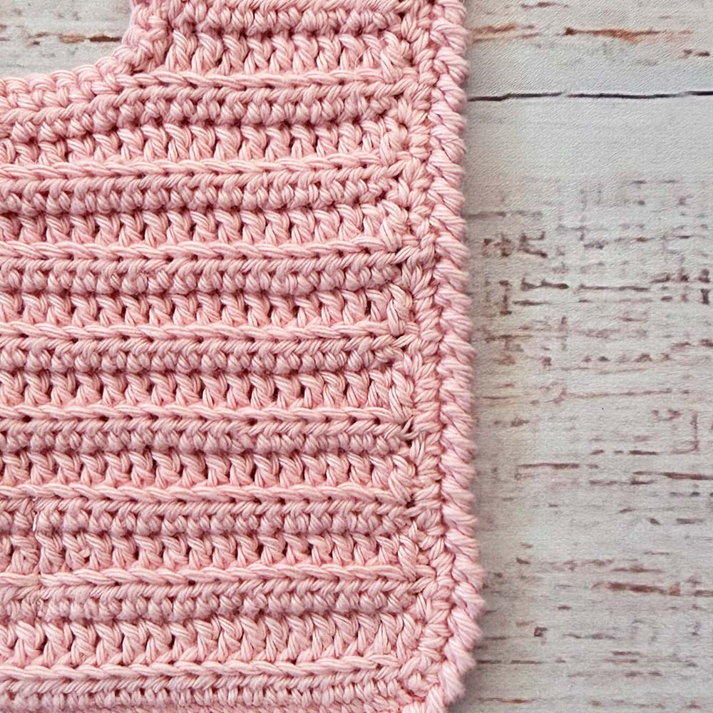 Babero de crochet rosado en vista del tejido con puntos en relieve