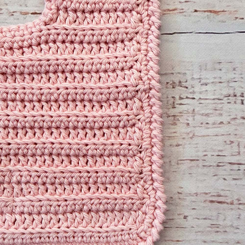 Babero de crochet rosado en vista del tejido con puntos en relieve