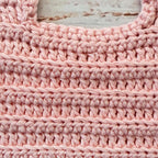 Babero de crochet rosado con textura uniforme y borde superior reforzado