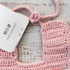 Babero rosado de crochet con cordón trenzado y forma rectangular