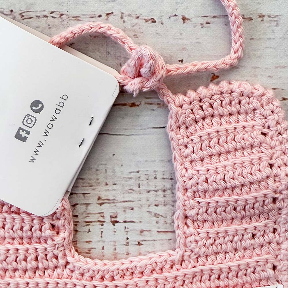 Babero rosado de crochet con cordón trenzado y forma rectangular