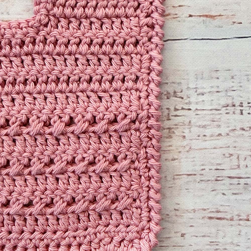 Babero de crochet palo rosa con tejido en punto trenzado