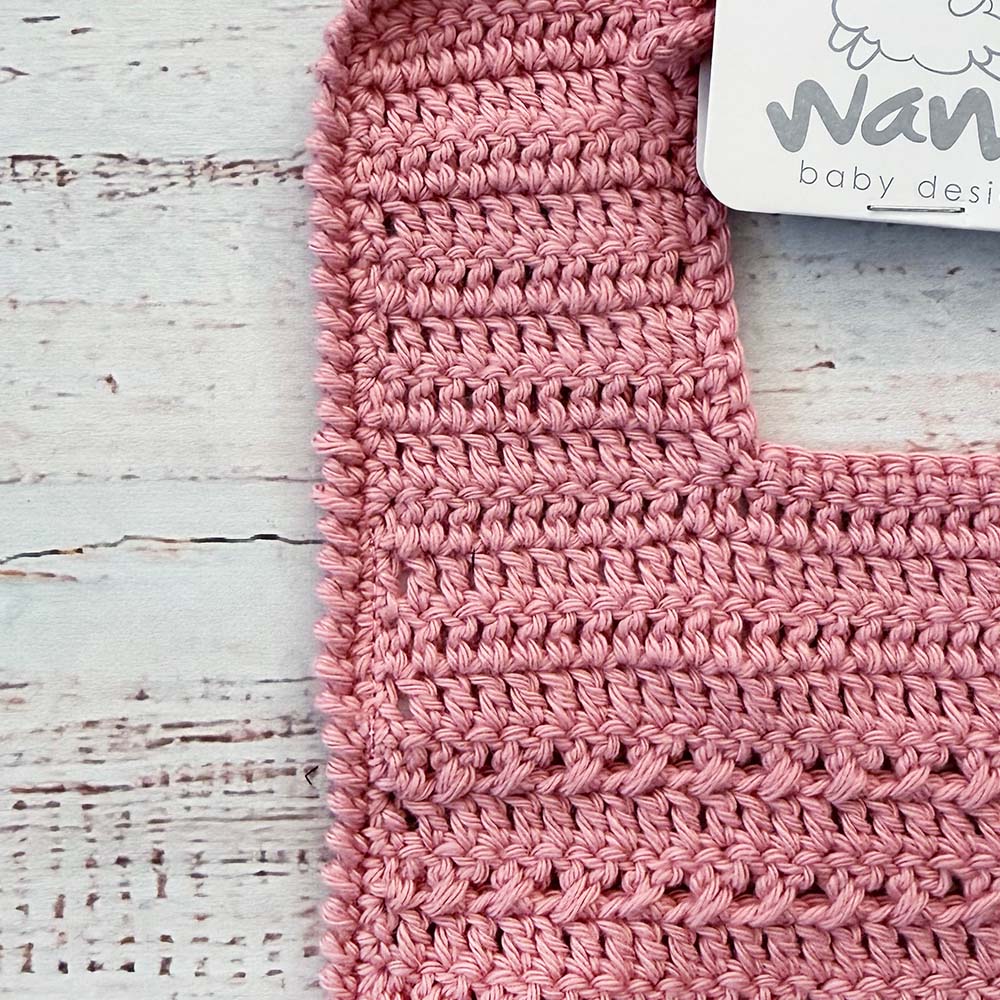 Babero de crochet palo rosa con etiqueta y borde superior